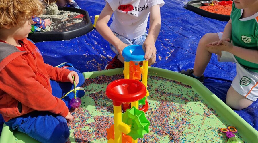 Young children play on a mat on a pitch.