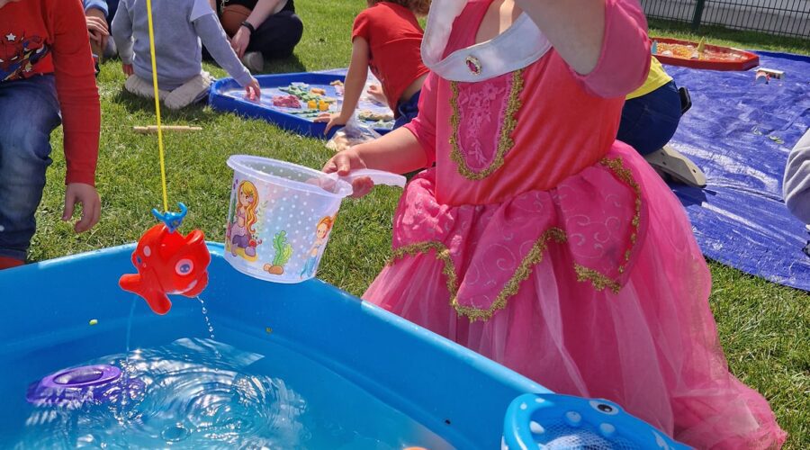 Young girl in a princess dress plays with a small toy fish pond.