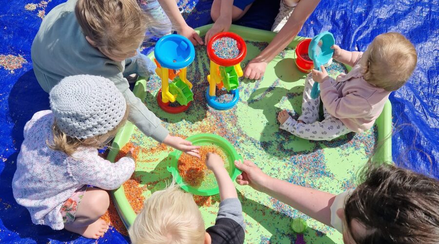 Young children play on a mat on a pitch.