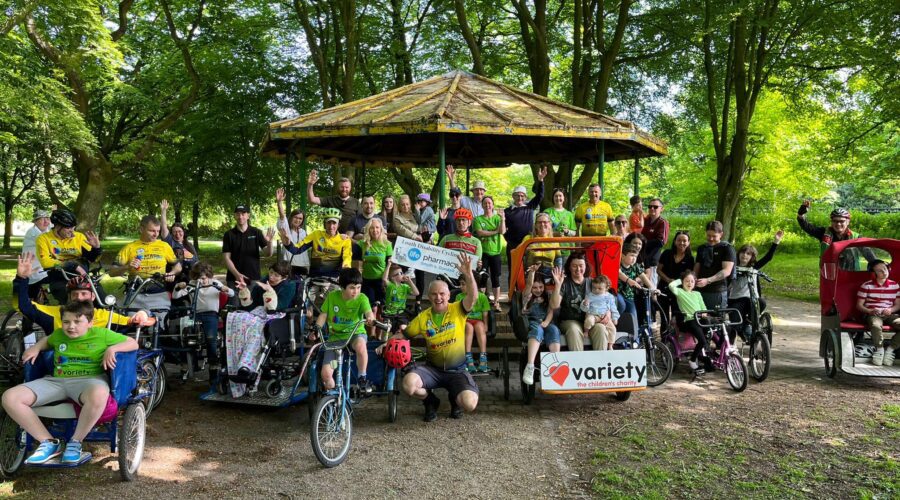 Group of people of all ages pose for picture for a disability cycle.