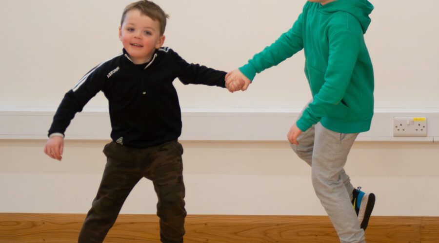 Two young kids dance while holding hands.