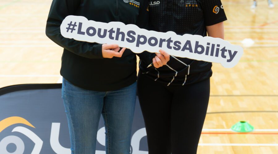 Two women hold sign for #LouthSportsAbility