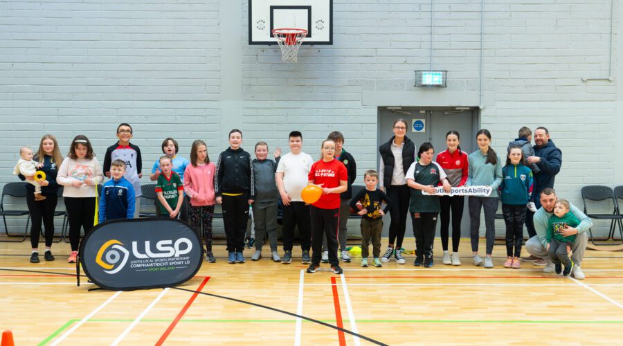 Group of people pose in gymnasium with signage for LLSP and #LouthSportsAbility.