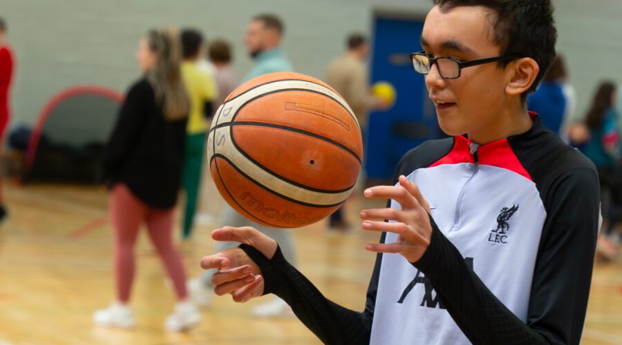 Young boy throws basketball in air.