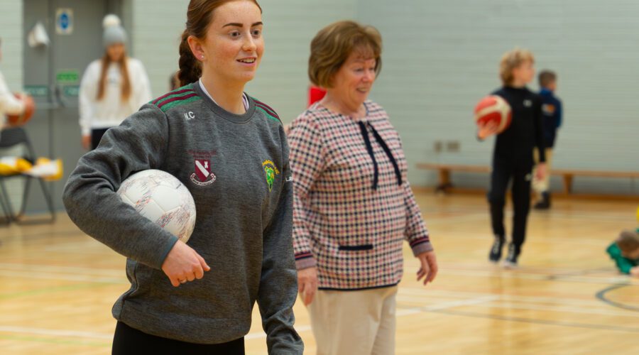 Woman holds volleyball in gymnasium.