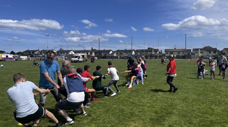 Group play tug of war on a pitch.
