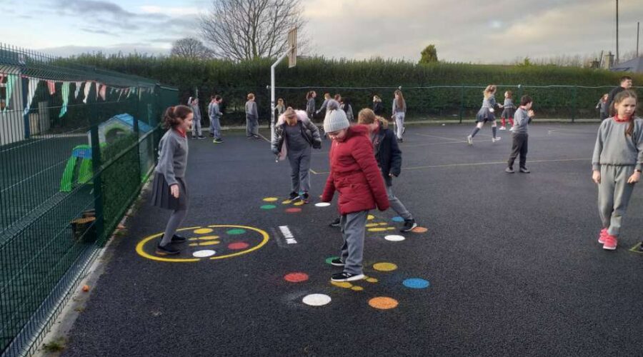 Children play hopscotch in a school playground.