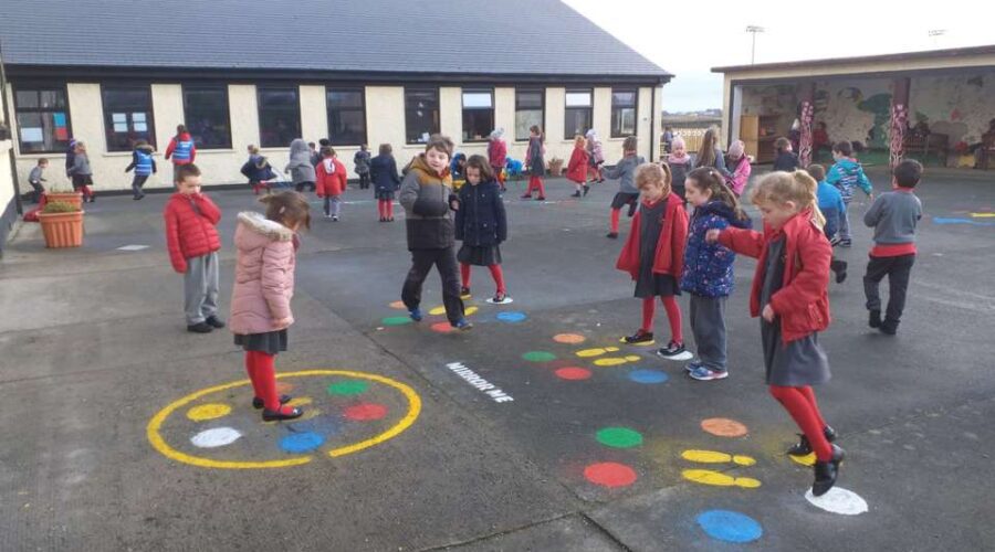 Children play hopscotch in a school playground.