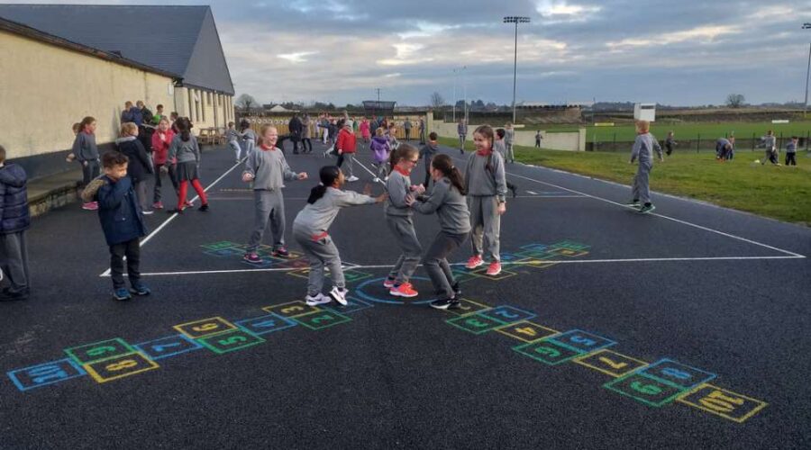 Children play hopscotch in a school playground.
